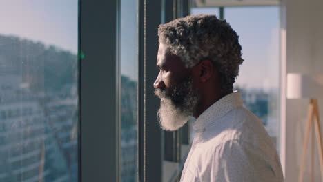 mature african american businessman looking out window planning ahead thinking of ideas for future business development with view of city at sunset 4k