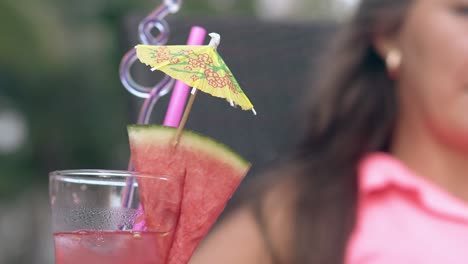 lady-sits-on-lounge-chair-behind-glass-with-beverage