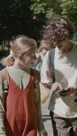 Young students using a smartphone together outdoors