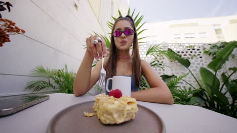 young woman with sunglasses enjoying dessert at an outdoor cafe