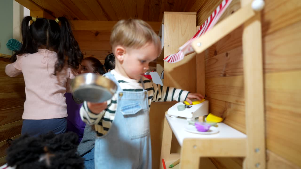 Süßer Kleinkindjunge spielt mit Spielzeugwaage und Obst im Spielzimmer