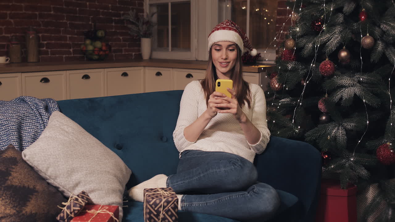 mujer usando el teléfono cerca del árbol de navidad
