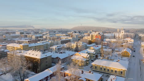 aerial view backwards over snowy streets of kuopio city, winter sunrise in finland