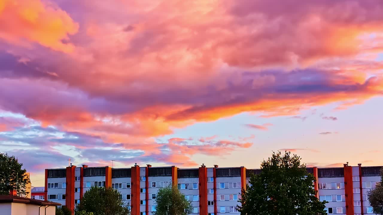 Vibrant pink-orange clouds above Soviet-style apartment block in Valmiera, Latvia