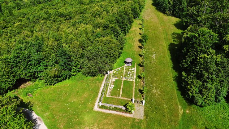 Approaching the gazebo on the green meadow surrounded by the lush forests. Aerial perspective on the stunning scenery of nature in the rocky landscape.