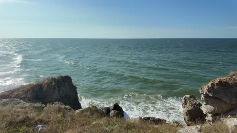 Waves-gently-crash-against-the-rocky-coast-of-Crimea,-showcasing-the-natural-beauty-of-the-Sea-of-Azov-on-a-sunny-day