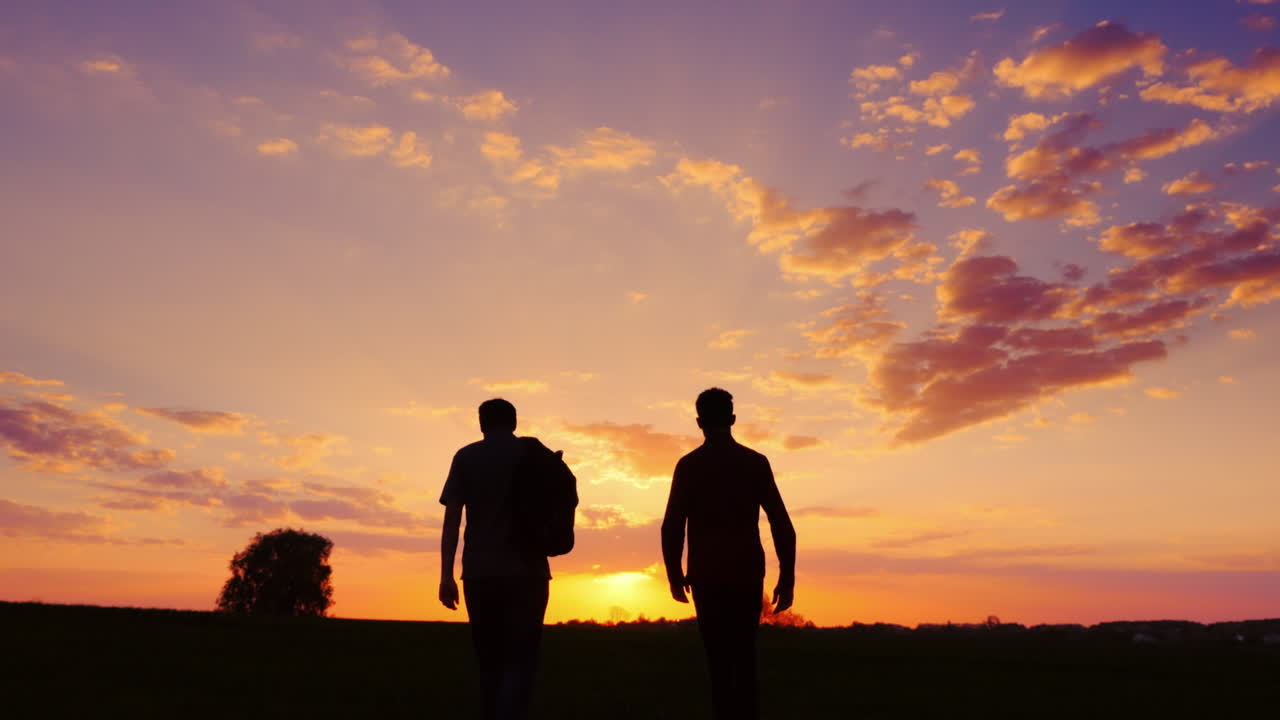 sagome di due uomini - figlio e padre vanno insieme per incontrare il tramonto