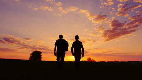 silhouettes of two men - son and father go together to meet the sunset