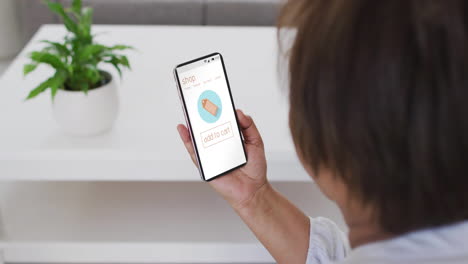 mujer biracial en casa usando teléfono inteligente para comprar en línea, cámara lenta