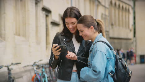 happy same sex female couple sightseeing as they pose for selfie and walk around oxford uk together