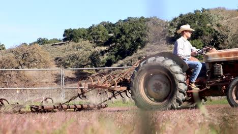 rancher towing harrow in a small round pen