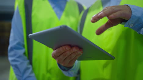 trabajadores de almacén de primer plano comprobación de información de tabletas inspección de fabricación