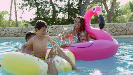 family having fun on inflatables in outdoor swimming pool