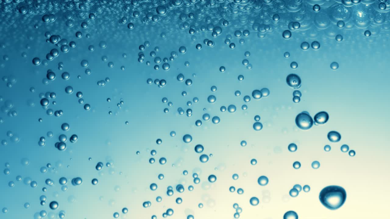 много водяных пузырьков в голубой воде вблизи, абстрактная водная волна с пузырьками в замедленном движении.