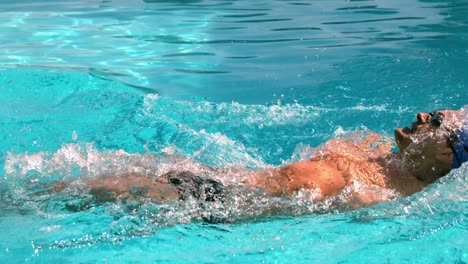 fit swimmer doing the back stroke in the swimming pool