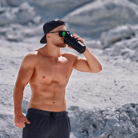 bodybuilder resting and drinking protein shake after exercising. concept of sport outdoors.