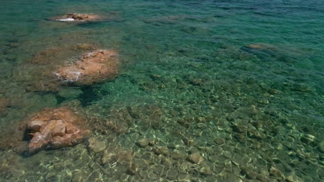 Wunderschönes-Tropisches-Kristallklares-Wassermeer-Mit-Felsen-Aufgetaucht-Und-Festgemachten-Booten-Unter-Der-Sommersonne-In-Sardinien,-Italien---Luftdrohnenaufnahme