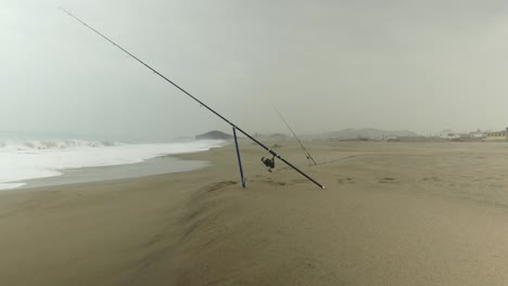 2-fishing-rods-on-the-sand-being-held-up-by-a-sand-spike