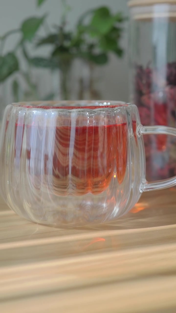 Tazza di vetro di infuso di ibisco rosso su un tavolo di legno