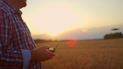 a-senior-adult-farmer-in-a-cap-uses-a-drone-to-fly-over-a-field-of-wheat.-An-elderly-farmer-uses-a-controller-to-control-the-drone.-Modern-technologies-in-agriculture