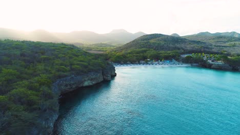 Aerial-side-dolly-along-rocky-coastline-reveals-Grote-Knip-Curacao-at-sunrise