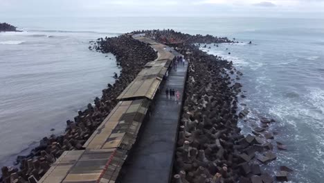 vista aérea de las olas del mar rompiendo bloques de tetra concreto o piedra rompeolas en la playa de glagah, indonesia por la mañana