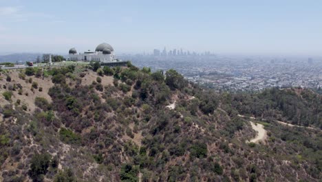 Toma-Aérea-Del-Observatorio-Griffith-En-Primer-Plano-Y-El-Horizonte-De-Los-ángeles-En-Segundo-Plano