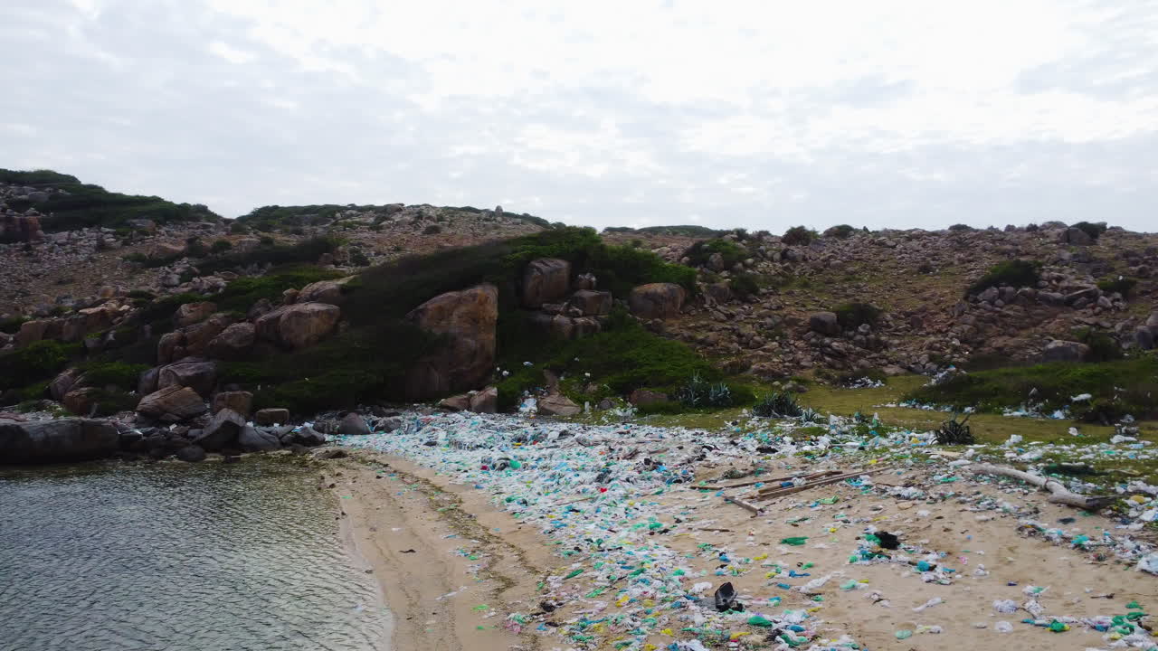 다채로운 비닐봉지로 가득 찬 닌 투언의 오염된 해변의 공중 원형 전망