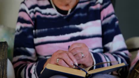 Senior-woman-reading-a-book-in-living-room-4k