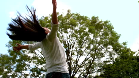 una morena despreocupada arrojando el cabello en el parque.