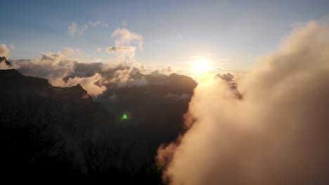 flight between glowing clouds during a sunset in the swiss alps as the sun disappears behind clouds and mountain peaks