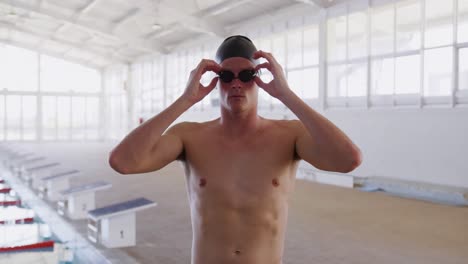 Swimmer-taking-off-his-pool-goggles-and-looking-at-camera