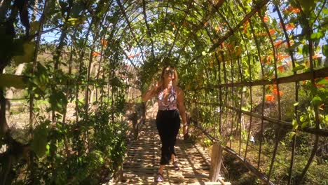 hermosa joven turista rubia cruza un puente de bambú cubierto mientras disfruta de la hermosa vista en pai tailandia