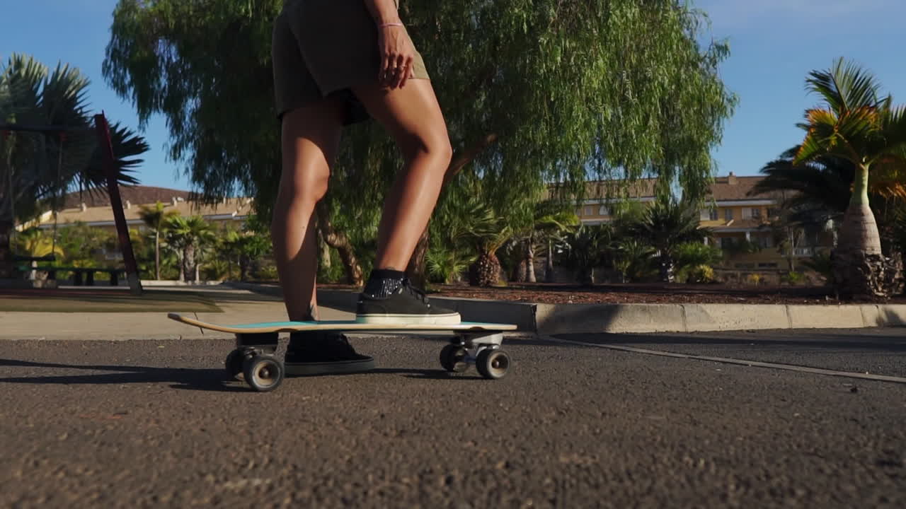 con palmeras como testigos, una mujer joven en cámara lenta monta una tabla larga durante el verano, su atuendo con pantalones cortos y zapatillas de deporte