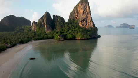 Railay-Beach,-Thailand-Bei-Sunrisre-Mit-Klippen,-Einem-Einzigen-Longtail-Boot-Und-Sanften-Wellen