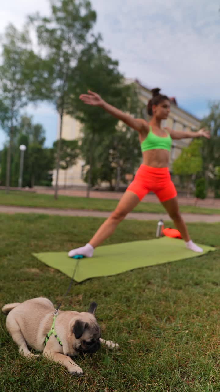 mujer practicando yoga en un parque con su pug