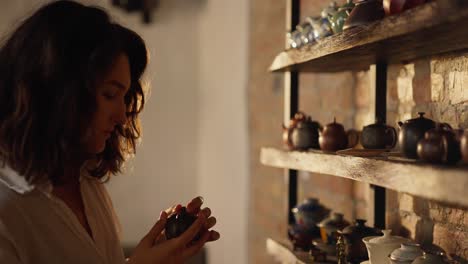 woman holding a teacup and teapot in a rustic setting