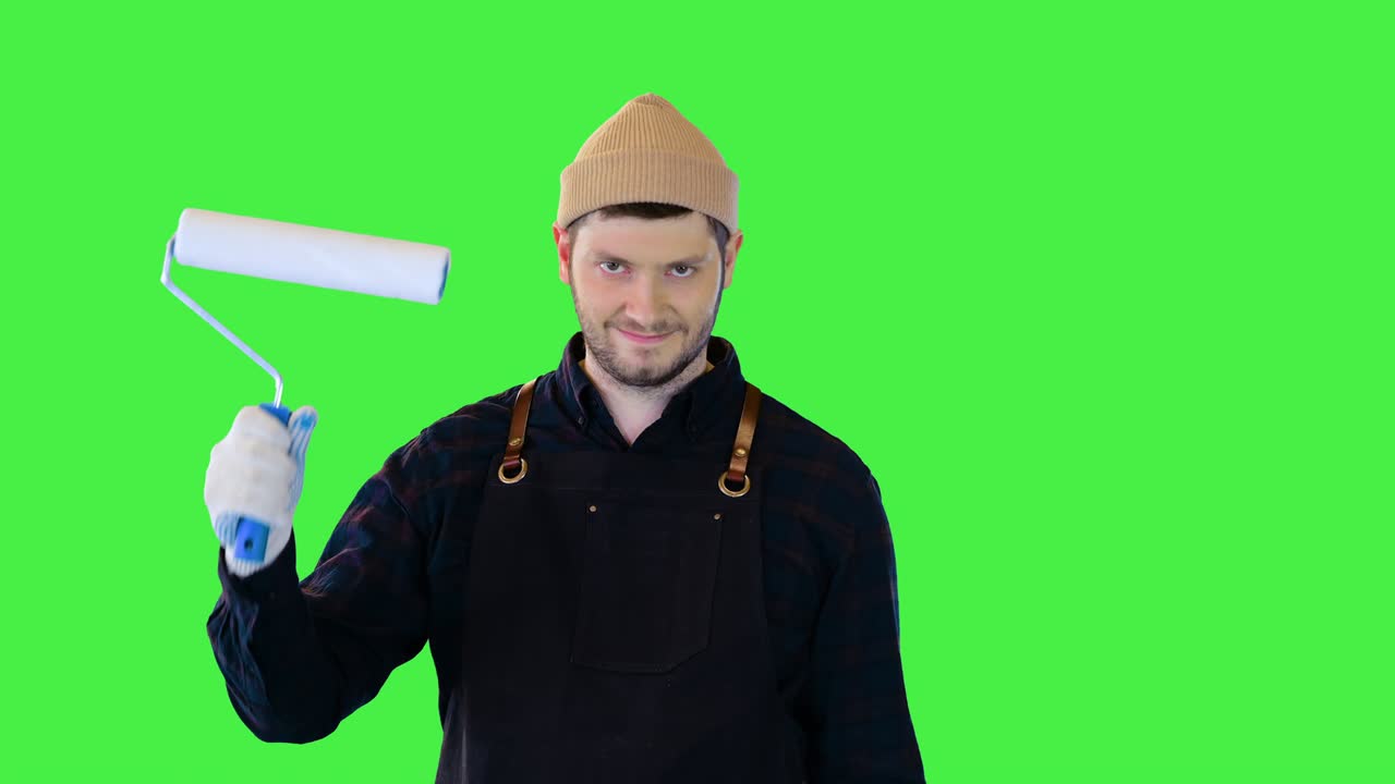 Felice operaio edile professionista guarda felicemente le pareti ristrutturate con rullo e pennello in mano su Green Screen, Chroma Key.