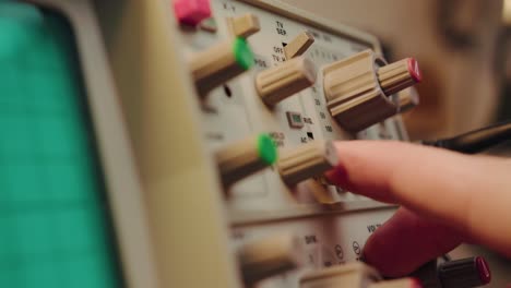 primer plano conectando un cable, operando una perilla y manipulando un dispositivo electrónico vintage altamente sofisticado