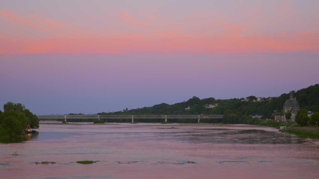 프랑스 소무르의 조용한 루아르 강을 가로지르는 교통 다리와 함께 놀라운 다채로운 일몰 하늘의 을 설정합니다.