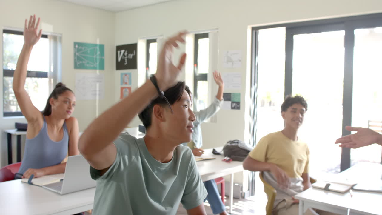 In high school, students raising hands in classroom, participating in discussion