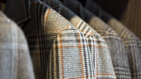 grey patterned tweed jackets hanging in wooden wardrobe, close up