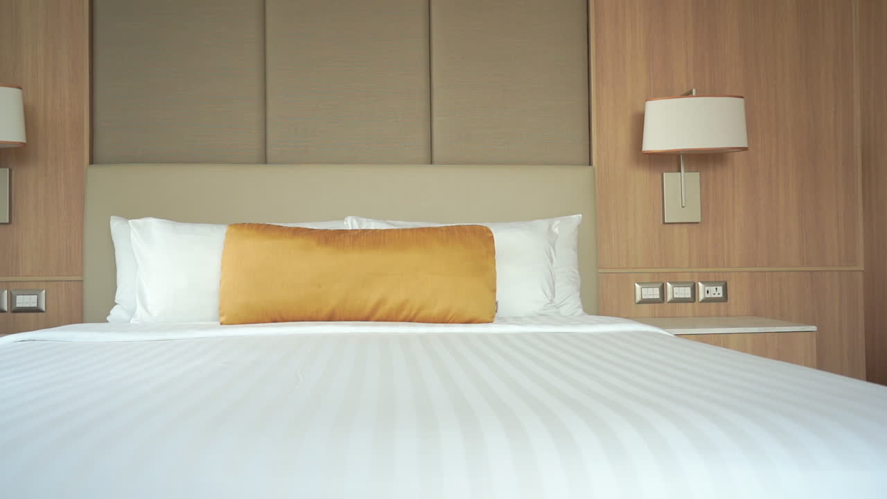 금으로 덮인 장식용 베개를 얹은 호텔 스위트 침대를 가로지르는 느린 팬