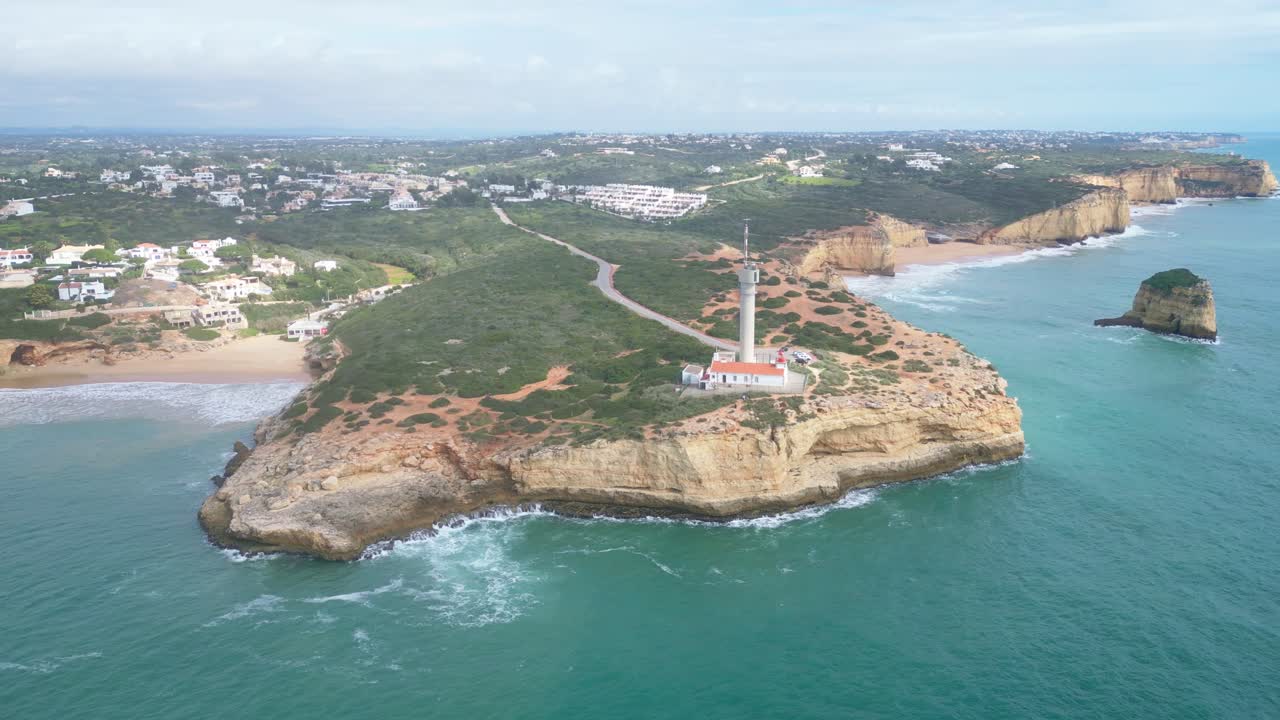 Lighthouse on a cliff near Ferragudo, Algarve, surrounded by sea and green hills