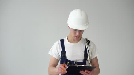master or assistant makes notes on a white wall background during repairs in the house