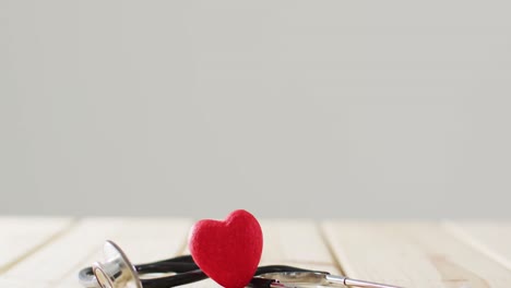 vídeo de un estetoscopio con un corazón rojo sobre fondo gris con espacio para copiar