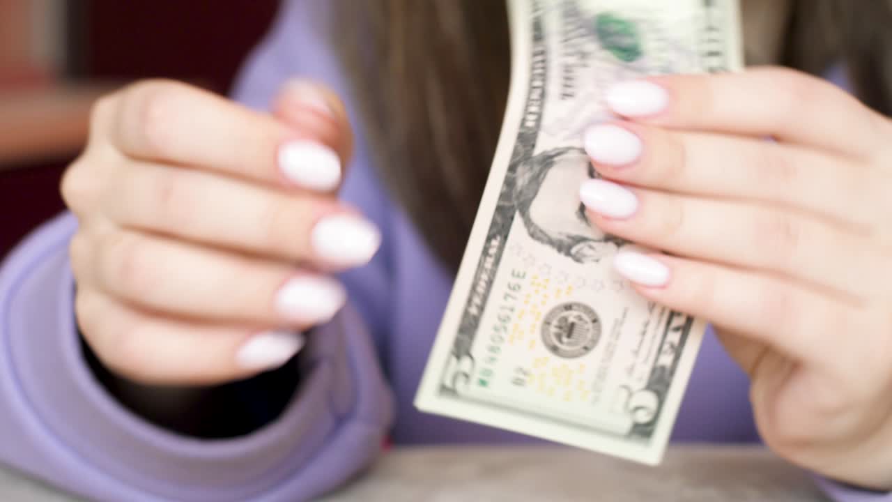 Close-up in women's hands 5 dollar bill. A woman holds in her hands examines a bill of 5 American dollars. selective focus. Cash paper american money theme