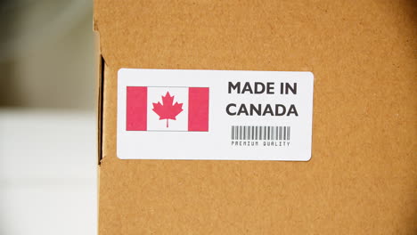 hands applying made in canada flag label on a shipping cardboard box with products