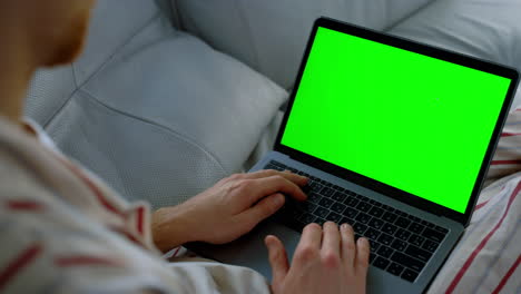 hombre de negocios usando una computadora portátil chromakey en un primer plano en el sofá. estudiante estudiando el fin de semana