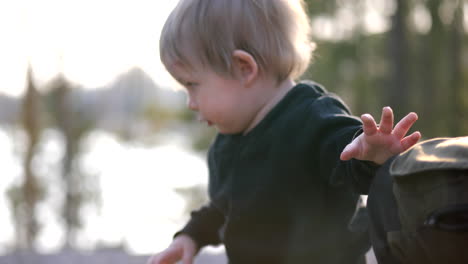 portrait shot of little baby boy in rural environment with bokeh lake in the background